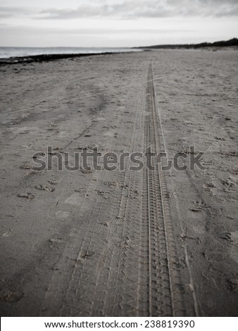 car tyre tracks on the beach sand in perspective - retro vintage 80's film look