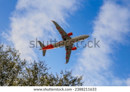 Close up low-flying white passenger plane with landing gear on a background of blue sky with clouds with copy space, bottom view. Italia, San Donato Milanese, Malpensa airport