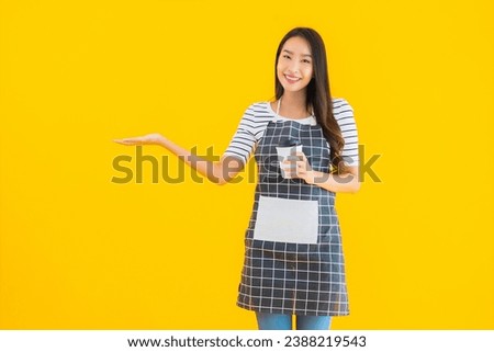 Portrait beautiful young asian woman wear apron with smile happy on yellow isolated background