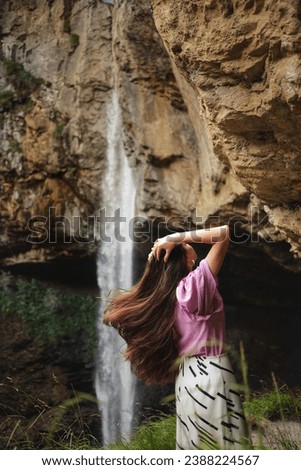 Long, thick, healthy, natural hair on the background of a waterfall.
An ideal photo for advertising shampoo, conditioner or hair rinse. Advertising of hair care products. . A girl, a model, a chic bil