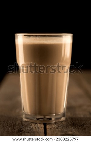 Glass of coffe with milk on a dark background. Hot latte or Cappuccino prepared with milk on a wooden table with copy space