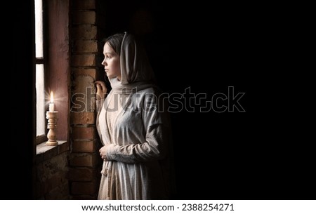 Lone retro rural veil cloth jew slave maid life sad poor lady face look cry plead bible Jesus. Holy cold kid child think ask beg old biblical god Christ wait even flame light war home room text space Royalty-Free Stock Photo #2388254271