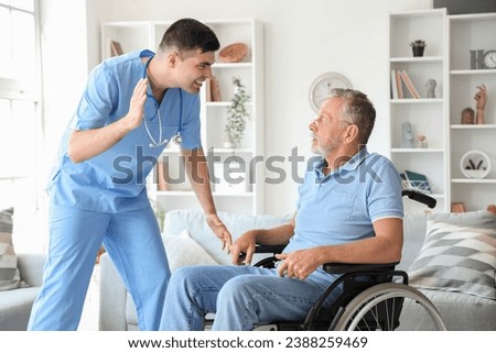 Senior man in wheelchair scared of angry nurse at home Royalty-Free Stock Photo #2388259469