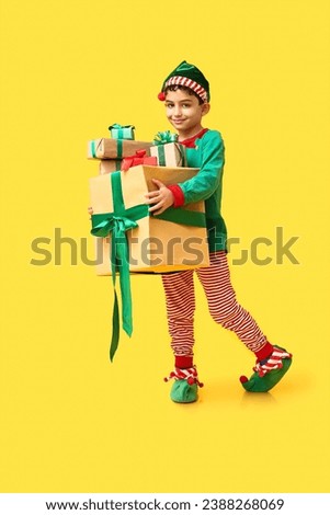 Cute little elf with Christmas gifts on yellow background