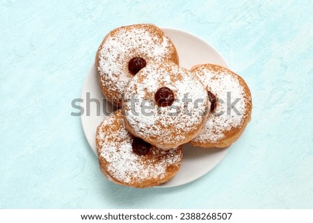 Plate with with tasty donuts for Hanukkah celebration on light background