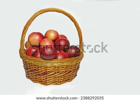    Wicker basket with ripe, natural red and yellow apples on an isolated white background.                            