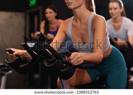 Group of women training on exercise bikes in fitness club, closeup