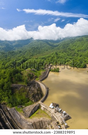 panoramic view of hydroelectric dam, clear sky and sunny day, lush forest in the background, lake and forest
