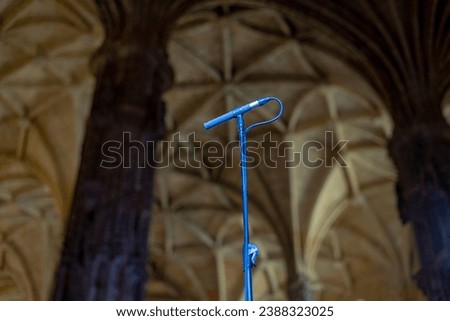 Broadcast microphone on support observed against the backdrop of the ceiling in the vault of a church or basilica