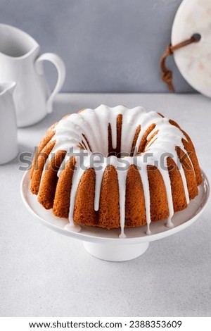 Vanilla bundt cake with sugar powder vanilla icing on a cake stand Royalty-Free Stock Photo #2388353609