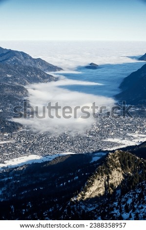 mountain landscape and aerial view of Garmisch-Partenkirchen, Bavaria, Kreuzeck, Germany, fog cloud enters the valley Royalty-Free Stock Photo #2388358957