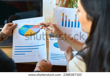 A cohesive group of businessmen collaboratively working as a team, engaged in a comprehensive analysis of numbers and graphs within the confines of a modern office. Royalty-Free Stock Photo #2388387103