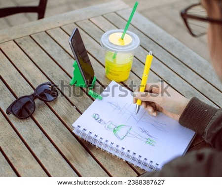 Woman designer creating clothing sketches during the day.