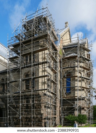 Restoration of the facade and roof of an old Lutheran stone church using complicated shaped scaffolding, blue sky background