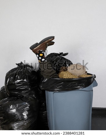 Portrait of Man in Suit and Hat Stuffed in a Garbage Can Surrounded by Trash Bags. Concept of Businessman Thrown Away.