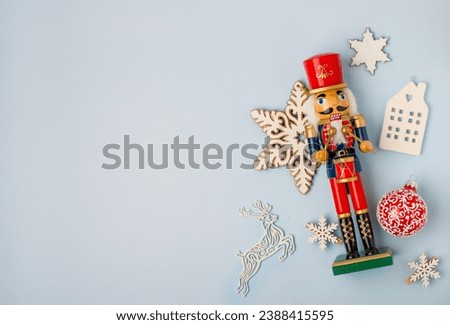 Christmas traditions, advent. Wooden toy Nutcracker on a light background with Christmas decor, space for text, horizontal.
