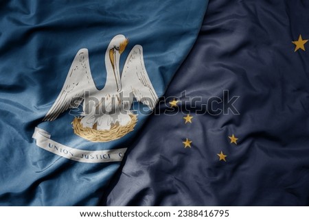 big waving colorful national flag of alaska state and flag of louisiana state . macro