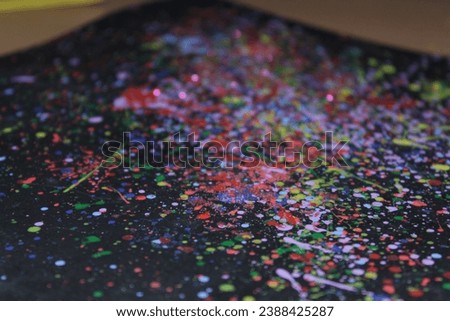 colored paint splashes on a dark sheet