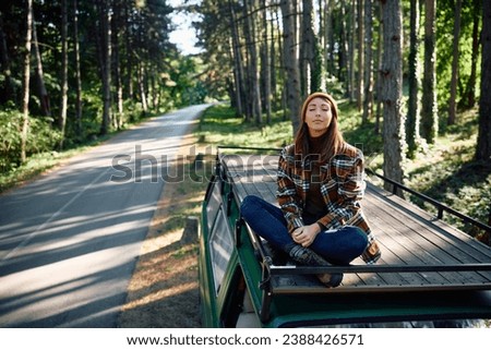 Relaxed woman with eyes closed breathing fresh air while camping in the woods. Copy space.
