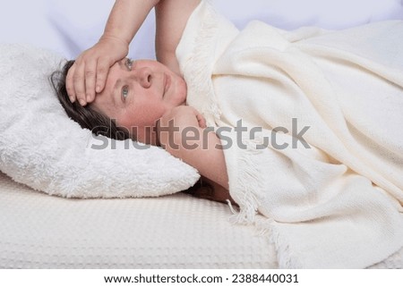 woman 45 years old can't fall asleep covered with white blanket, experiencing insomnia, Insomnia Management concept, Sleep disturbances in menopause Royalty-Free Stock Photo #2388440031