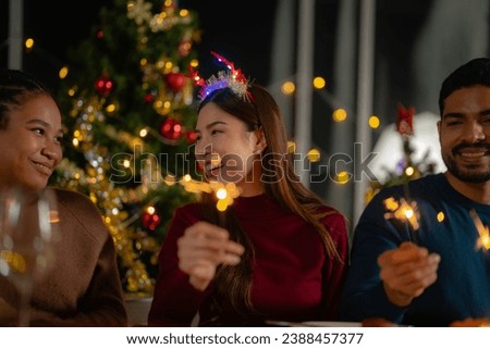 happy female and friends holding sparkler fireworks in a party with Christmas tree. young Asian people enjoy celebrating Christmas and New Year. celebrate with food wine and friendship for love,