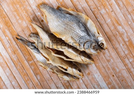 Pile of eviscerated dried roaches served on wooden table. Bunch of stockfish.