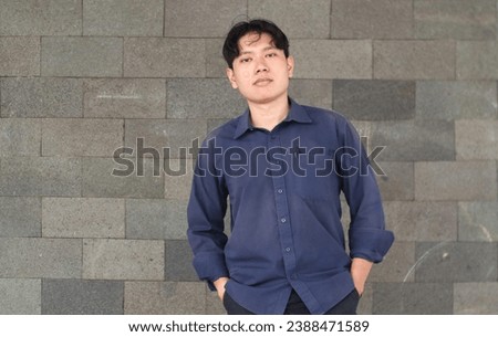 A handsome Asian  man Smiling stands confidently wearing a shirt navy blue