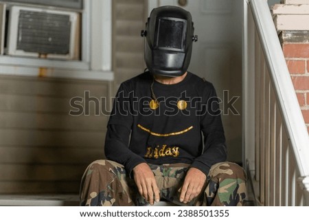 man wearing a welders mask and wearing a Friday shirt 