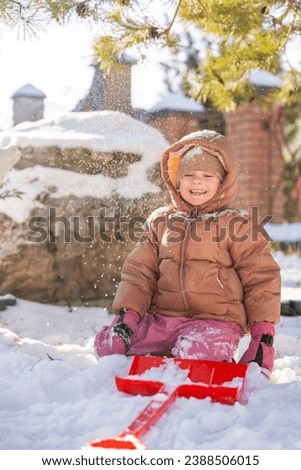 Laughing child playing with snow in the backyard of the house in winter, Christmas time. High quality photo