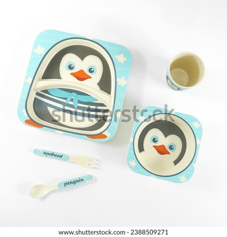 A set of plastic cutlery with penguin motifs on a white background, flat lay. Serving baby food