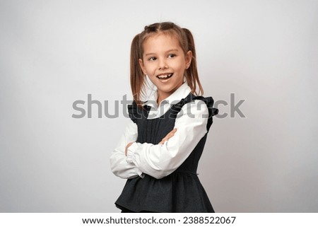 Portrait of cute little girl standing with crossed arms, posing over white background with copy space