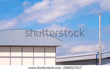 Industrial warehouse and factory buildings with large chimney against blue sky background 