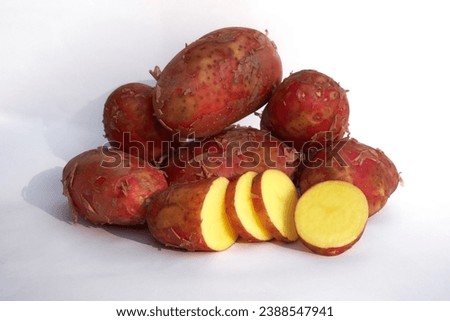 Red potatoes, whole tubers and cut slices with yellow flesh on white background, close-up, horizontal photo, fresh crop of young potato.