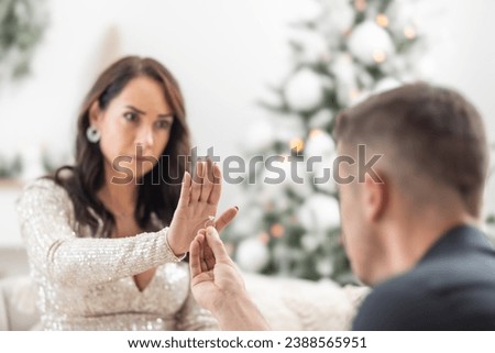 Woman declines a proposal to a man kneeing in front of her with a ring in his hand during Christmas.