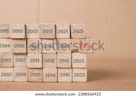 Photo of wooden block rows with gray numbers of passed years and one of them standing out with red number 2024 imprinted on wooden surface. New Year concept.