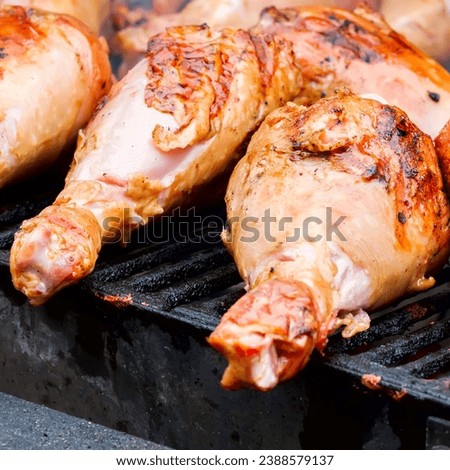 Close-up of appetizing turkey drumsticks grilling on charcoal stove, bbq grill meat - ready turkey legs on grid over charcoal