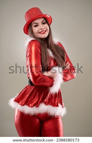 Beautiful Hispanic Santa girl in red costume, studio shot in Christmas theme