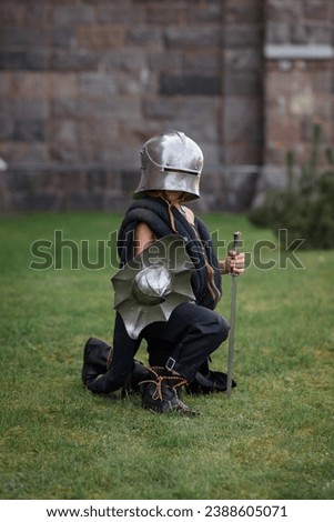 Make fealty. Portrait of serious manm medieval warrior, knight in armor sitting on one knee. Knight's noble oath. Comparison of eras, history, renaissance style