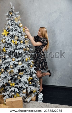 Woman decorating christmas tree with gifts