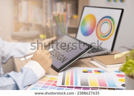 Designer creating graphic logo on a table using tablet and laptop