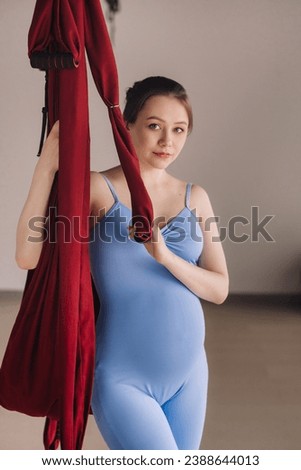 Pregnant girl. A woman in sportswear stands near a hanging hammock in the gym. The concept of a healthy lifestyle, motherhood.