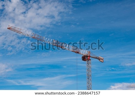 Construction background photo. Tower crane isolated on partly cloudy sky background. Construction industry or real estate concept photo.