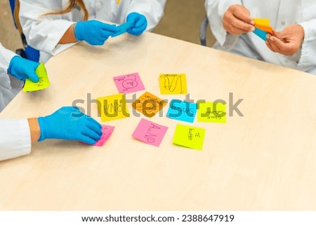 Close-up photo of group of scientists during a brainstorm study using notes in lab