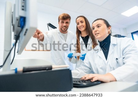 Happy doctors using computer and pointing to the screen in a research laboratory