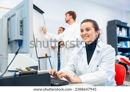 Smiling young scientist using computer in the office of a laboratory