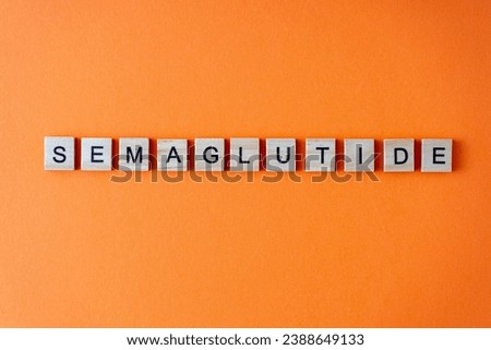 Word semaglutide. The phrase is laid out in wooden letters top view. Orange flat lay background Royalty-Free Stock Photo #2388649133