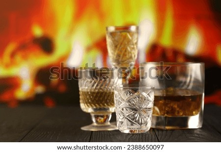 Different alcohol drinks in glass on wooden surface on fireplace background. Luxury elite alcohol in glass cups. Low key dark scene