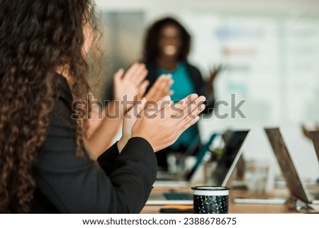 A room full of work colleagues clap their hands after a business presentation.