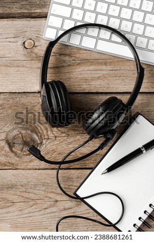 Customer service headset with office accessories on wooden desk. Top view 