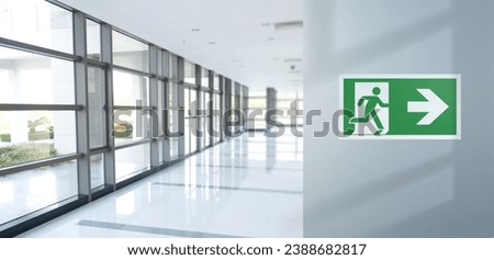 Fire exit sign on the right in the corridor of the office. Background space for copy text. Blue light effect. Royalty-Free Stock Photo #2388682817